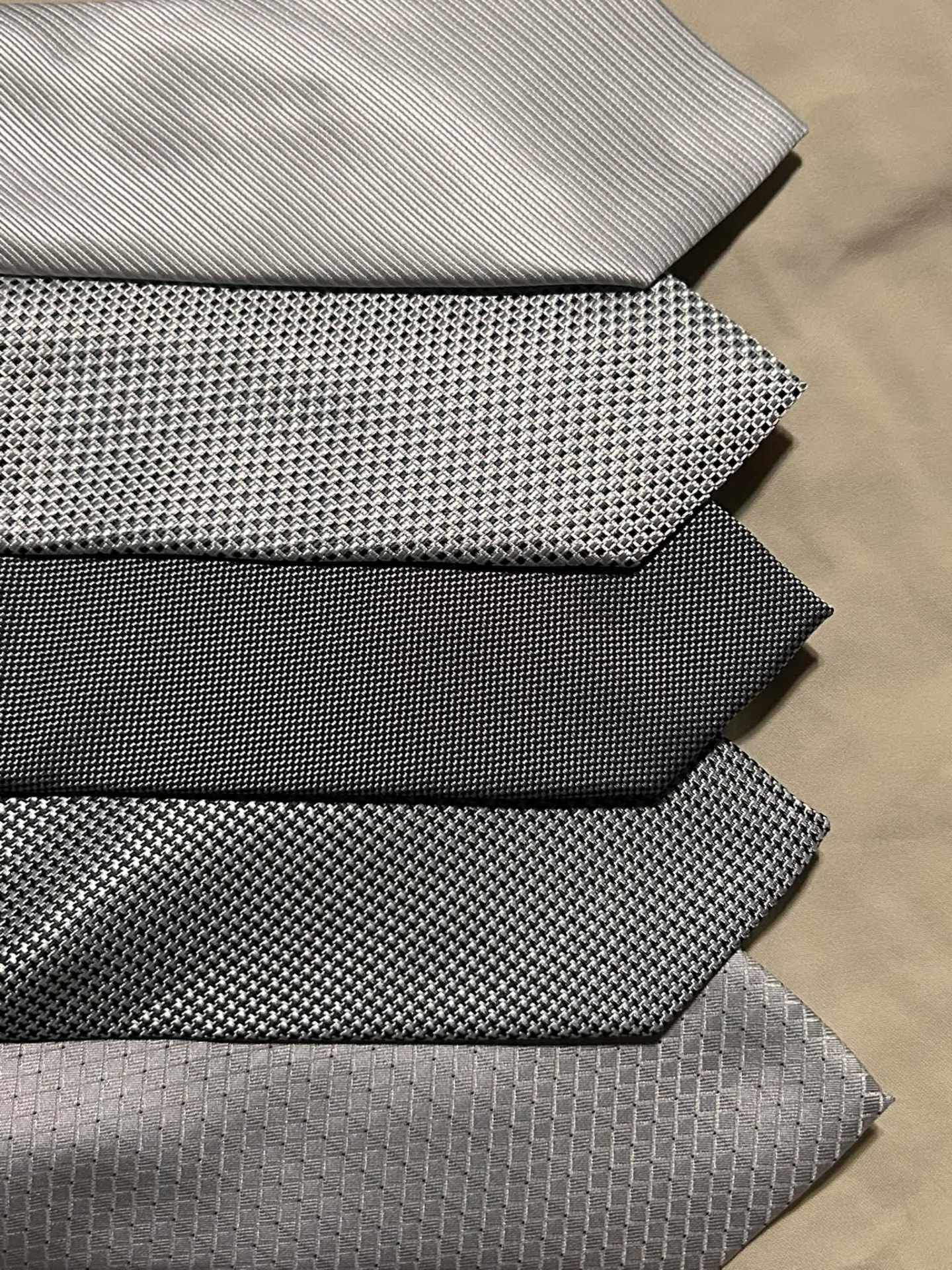 Stack of silver, charcoal, and gray textured neckties
